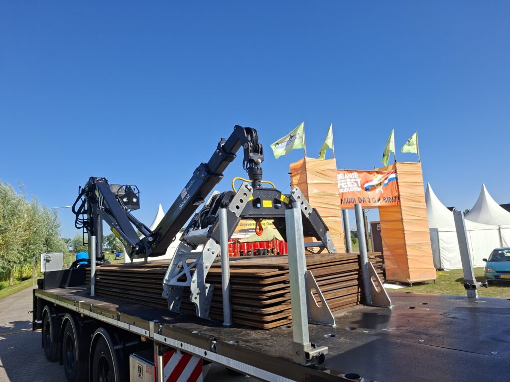 Kraanwagen van RVS Rijplaten levert stalen rijplaten bij een evenemententerrein, rijplaten huren voor evenementen
