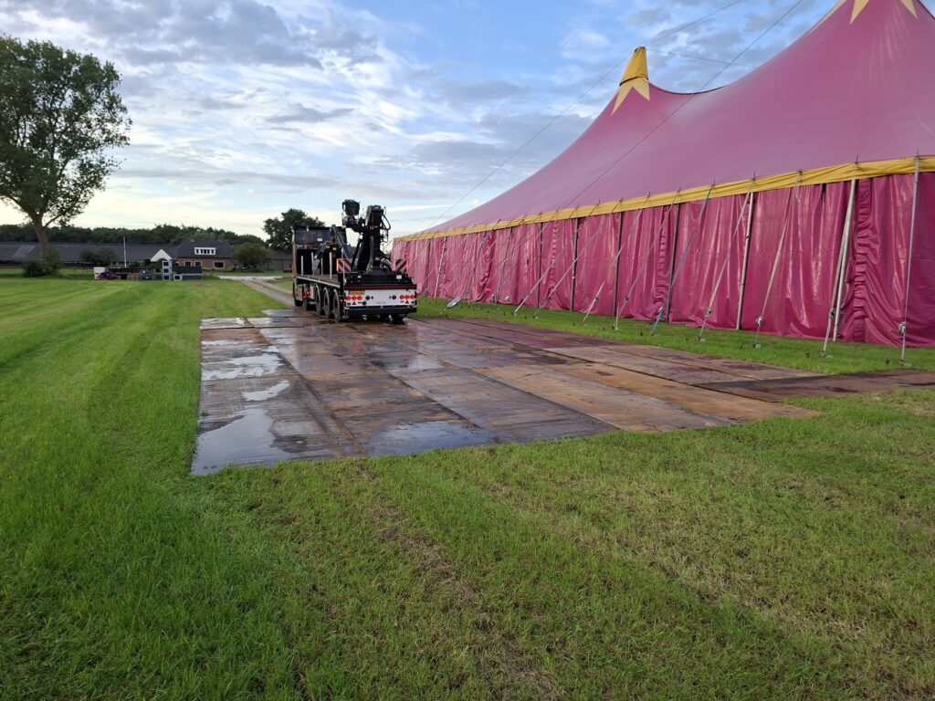 Stalen rijplaten als toegangsweg naast een feesttent op grasland, rijplaten verhuur RVS Dalfsen