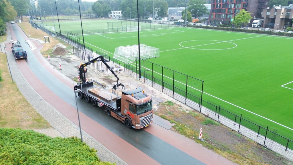 Dronefoto van rijplaten lossen op het sportpark van Universiteit Twente in Enschede