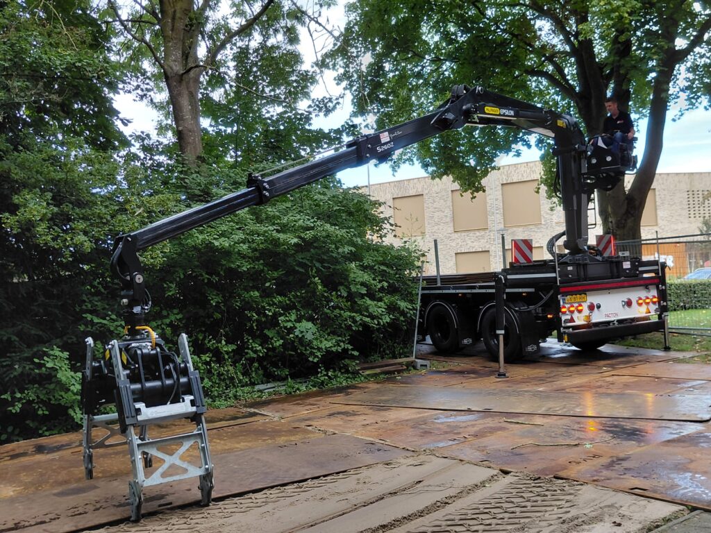 Kraan legt stalen rijplaten voor de opslag van bouwmateriaal bij Straatwerk Pekkeriet in Zwolle